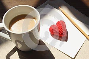 Red love hearts on brown paper note with a cup of coffee.