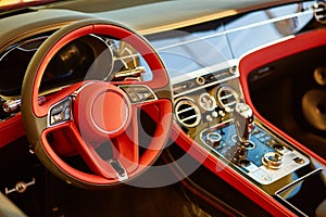 Red luxury car Interior. Steering wheel, shift lever and dashboard. Shallow doff