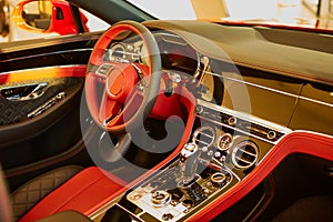 Red luxury car Interior. Steering wheel, shift lever and dashboard. Shallow doff