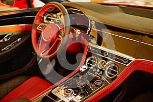 Red luxury car Interior. Steering wheel, shift lever and dashboard. Shallow doff