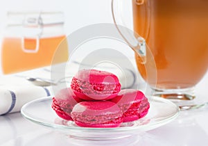 Red macaron cupcakes in a glass plate. Coffee in an Irish coffee glass, orange jam in a jar with a yoke. Linen napkin with a spoon