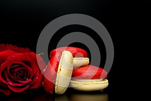 Red macaroon on black background with red roses