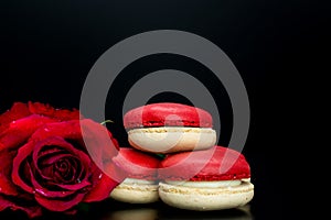 Red macaroon on black background with red roses