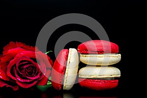 Red macaroon on black background with red roses