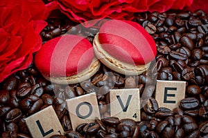 Red macaroon on rosted coffee beans background with red flowers and letters LOVE photo