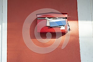Red mailbox with documents overflowing