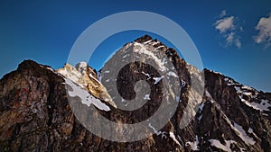 Red majestic rocks dusted with snow high in the mountains. Flying near high peaks and mountain tops at sunset. Aerial