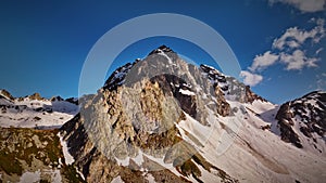 Red majestic rocks dusted with snow high in the mountains. Flying near high peaks and mountain tops at sunset. Aerial