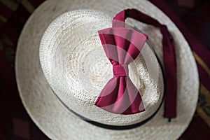 Red male bow-tie on a white wicker vintage hat.