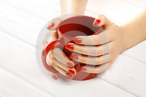 Red manicure with a cup of tea