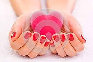 Red manicure with gift box on the white towel