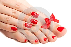 Red manicure and pedicure with a bow. isolated