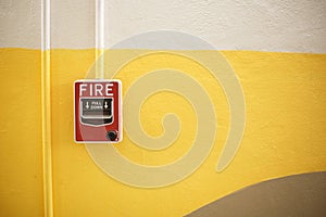 Red manual pull fire alarm safety system. Pull station or call point, manual fire alarm activation on yellow wall background with