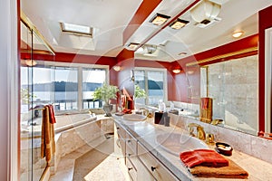 Red and marble interior of large luxury master bathroom with glass shower, and jacuzzi tub.