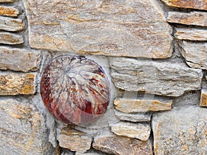 Red marbleized bowling ball embedded in a stone wall