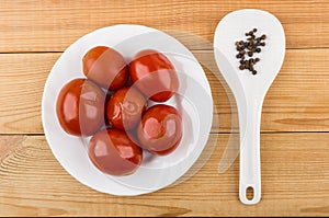 Red marinated tomatoes in white plate and black pepper