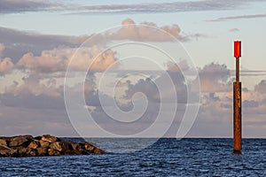 Red marker post at sea. Danger warning of rocks and shallow water