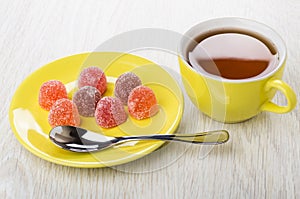 Red marmalade and teaspoon in saucer, cup of tea