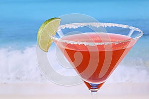 Red Martini cocktail with a lime on the beach
