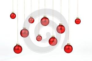 Red matt christmas balls hanging on golden strings on white background