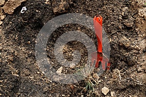 Red mattock on soil in afternoon light