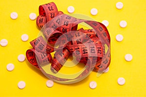 A red measuring tape for measuring the circumference of the body, abdomen, hips is on a yellow background, surrounded by white pil photo