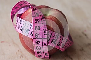 Red measuring tape with red apple closeup