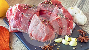 Red meat on a black Board sprinkled with pepper, garlic, anise and lime. Billets for barbecue,  steak or shish kebabs. Cooking for