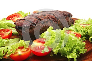 Red meat served on wooden plate with vegetables