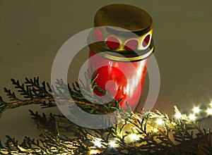 Red memorial candle with a green thuja twig and white lights. Red lighted candle holder with small tuja branch and LED