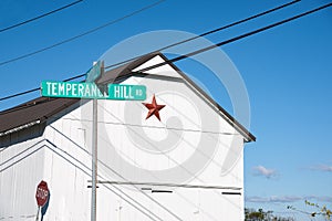 Red Mennonite star of exterior of simple white building by Temperance Hill Road street sign