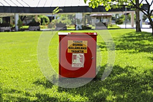 Red metal fire cabinet placed on the lawn in the garden in daylight