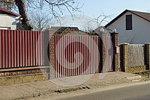 Red metal gate and door with part of the wall of the fence