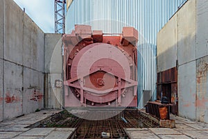 Red metal hermetic gateway door of airlock of nuclear reactor of abandoned unfinished power unit of nuclear power plant