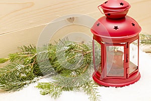 Red metal lantern has a burning candle.