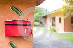 Red metal mail box on design clay wall over blurred house background