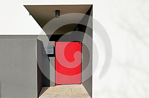 Red metal pedestrian gate of a modern black and gray building.