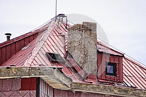 Red metal roof with broken chimney and open dormer