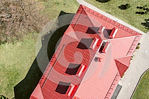 Red metal roof of house with vent pipes and dormer windows. drone photography