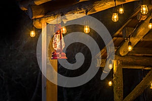 Red metal storm lantern hung outside rustic log cabin.