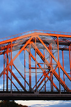 Red metallic bridge. Blue sky with clouds background.