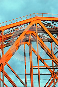 Red metallic bridge. Blue sky with clouds background.