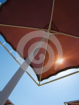 Red metallic parasol beach umbrella over blue sky