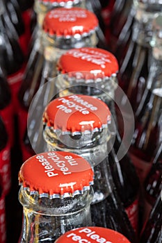 Red metals caps on the top of retro style coca cola bottles carrying the message `Please recycle me`.