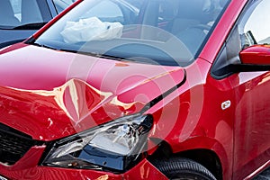 Red mini car severely damaged after traffic accident with deployed airbag