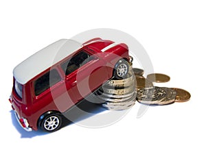 Red mini toy car against pile of British coins