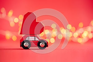 Red model of car delivering red paper heart on red background. Creative greeting card for Saint Valentine day