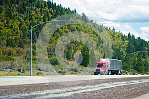 Red modern semi truck with low cab and soft tent trailer move on