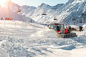 Red modern snowcat ratrack with snowplow snow grooming machine preparing ski slope piste hill at alpine skiing winter