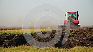 Red modern tractor with reverse plow plows the field. Agricultural work in the field, agribusiness